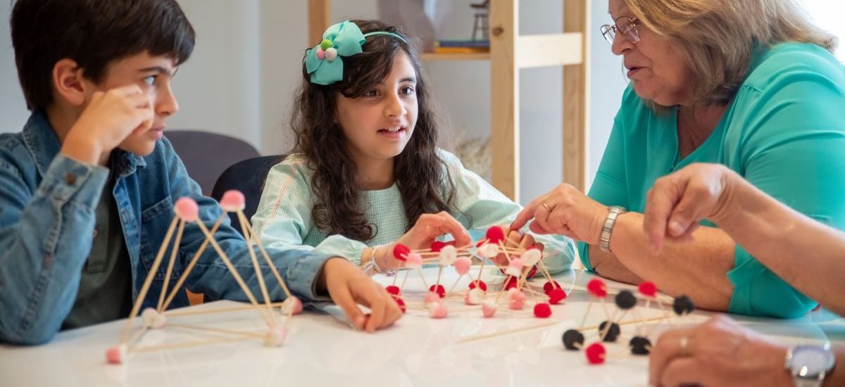 Grandmother playing educational games with grandchildren indoors, fostering creativity and learning.